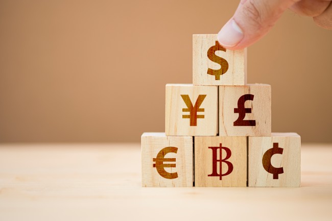 Woodblocks stacked with currency symbols on them