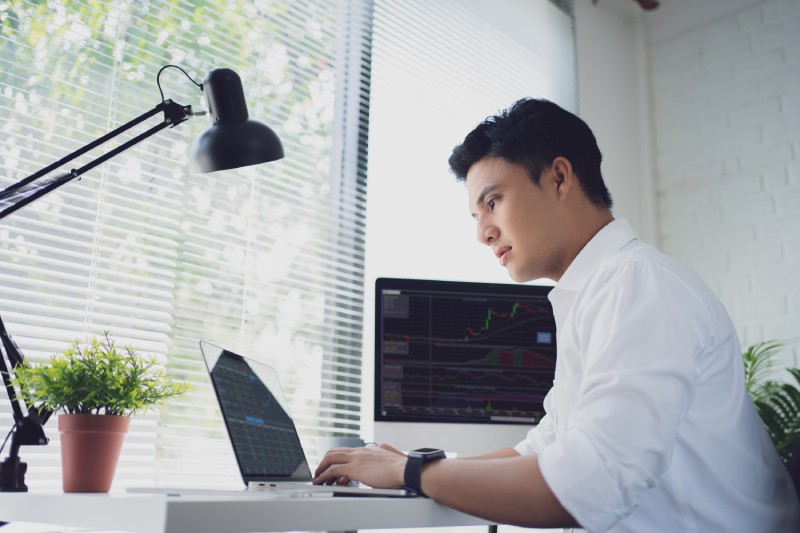 Man looking at trading charts on his laptop